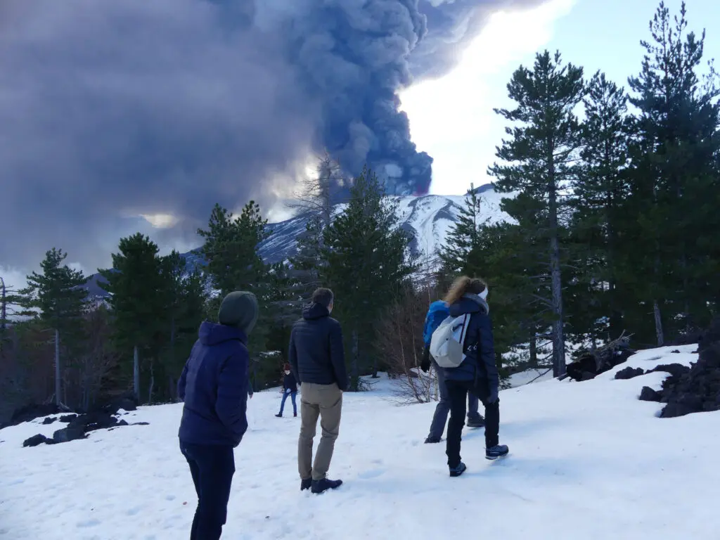 Hiking group resting on Mount Etna summit in winter conditions